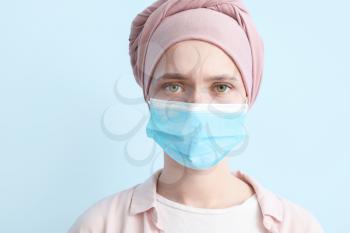 Woman after chemotherapy wearing medical mask on color background�