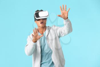 Teenage African-American boy with virtual reality glasses on color background�
