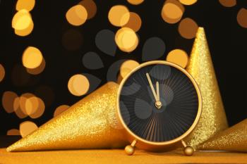 Alarm clock and party hats against blurred lights. Christmas time�