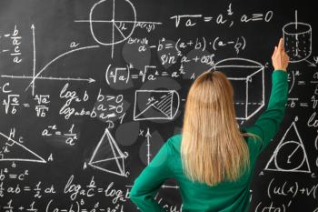 Mature maths teacher near blackboard in classroom�