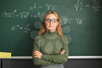 Mature maths teacher near blackboard in classroom�