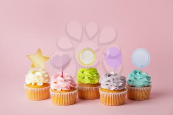 Tasty cupcakes with stylish toppers on color background�