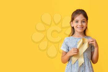 Little girl with golden ribbon on color background. Childhood cancer awareness concept�