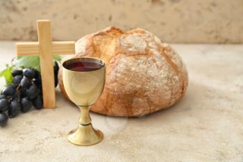 Chalice of wine with bread and cross on grey background�