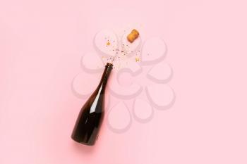 Bottle of champagne and glitters on color background. New year celebration�