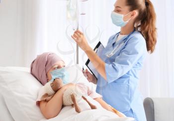 Nurse and little girl undergoing chemotherapy course in clinic�