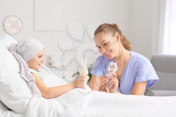 Woman visiting her daughter who is undergoing course of chemotherapy in clinic. Childhood cancer awareness concept�