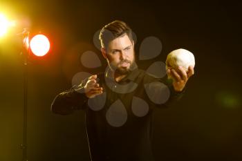 Male actor with human skull on stage�
