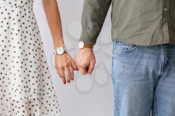 Young couple holding hands on light background�