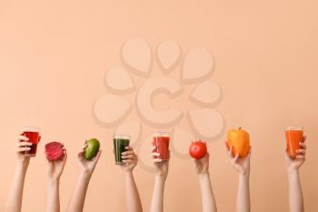 Many hands with glasses of vegetable juices on color background�
