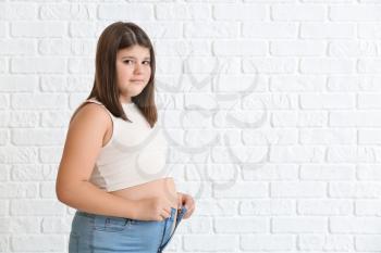 Overweight girl in tight clothes on white brick background�