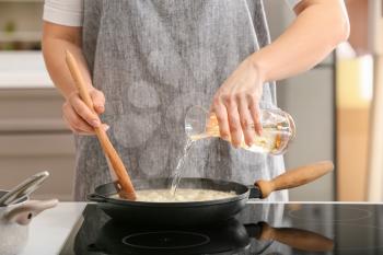 Woman cooking risotto in kitchen�