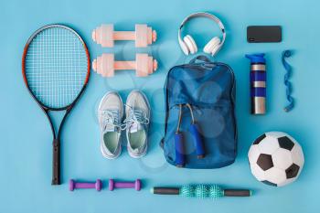 Set of sport equipment with backpack on color background�