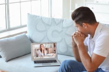 Stressed young man asking psychologist for advice online at home�
