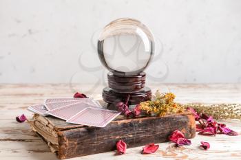 Spell book, crystal ball and cards on wooden table�