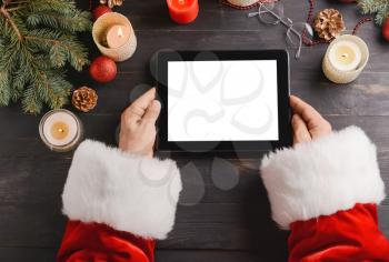 Santa Claus with tablet computer at table�