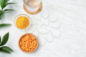 Bowls with turmeric pills and powder on light background�