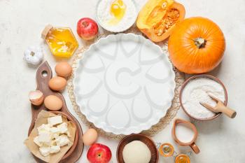 Ingredients for preparing pumpkin pie and baking dish on light background�