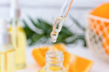 Orange essential oil dripping from pipette into bottle, closeup�