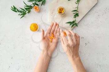 Female hands with turmeric pills, powder and roots on light background�