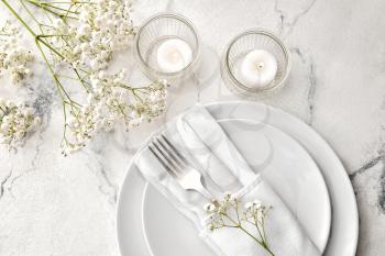 Beautiful table setting with burning candles and floral decor on light background�