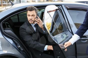 Businessman getting out of luxury car�