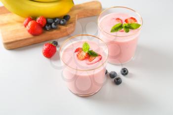 Glasses of tasty berry smoothie on light background�