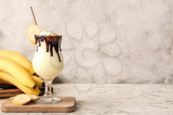 Glass of tasty banana milkshake on grunge background�