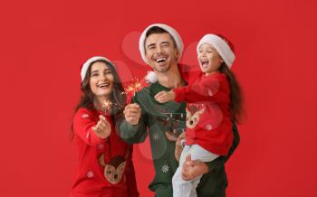 Happy family with Christmas sparklers on color background�