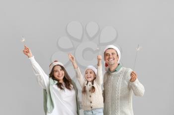 Happy family with Christmas sparklers on grey background�