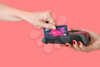 Woman paying for purchase via terminal on color background�