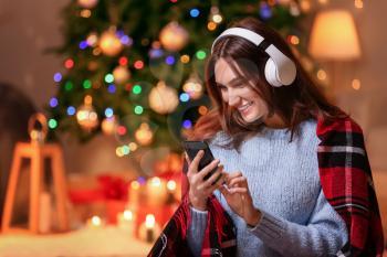 Beautiful young woman listening to Christmas music at home�