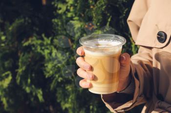 Woman drinking tasty latte outdoors, closeup�