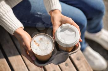 Woman with takeaway cups of tasty latte outdoors, closeup�