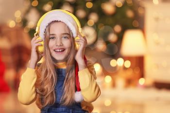 Cute little girl listening to Christmas music at home�
