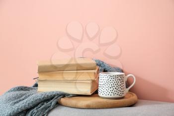 Books, plaid and cup of tea on color background�