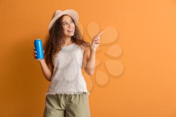 Beautiful African-American woman with soda pointing at something on color background�
