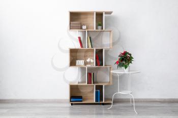 Modern shelf unit and table with houseplant near light wall�