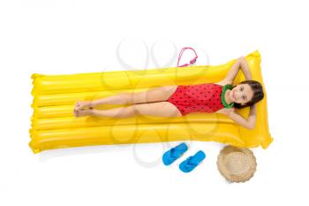Cute little girl lying on inflatable mattress against white background�