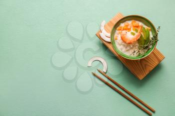 Bowl with Thai rice soup on color background�