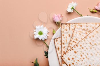 Plate with Jewish flatbread matza for Passover and flowers on color background�