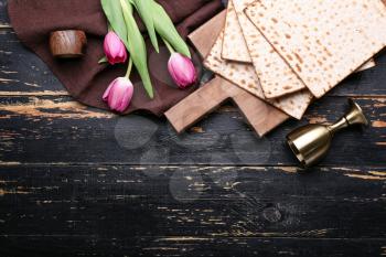 Composition with Jewish flatbread matza for Passover and flowers on dark background�