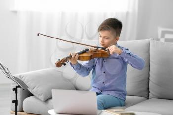 Little boy taking music lessons online at home�