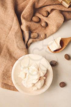 Plate with shea butter and nuts on light background�