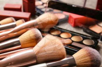 Set of makeup brushes with cosmetics on table, closeup�