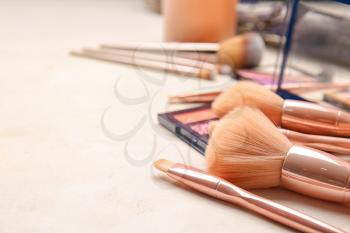 Set of makeup brushes with cosmetics on table�