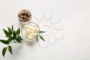 Bowls with shea butter and nuts on light background�