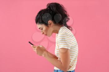 Young woman with bad posture using mobile phone on color background�