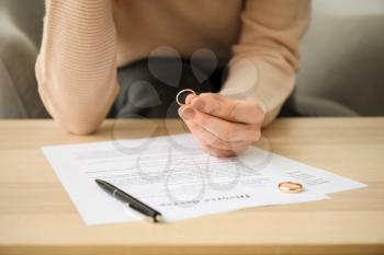 Woman with divorce decree and rings in lawyer's office, closeup�