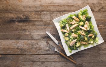 Plate of tasty salad with fresh vegetables and chicken on wooden background�
